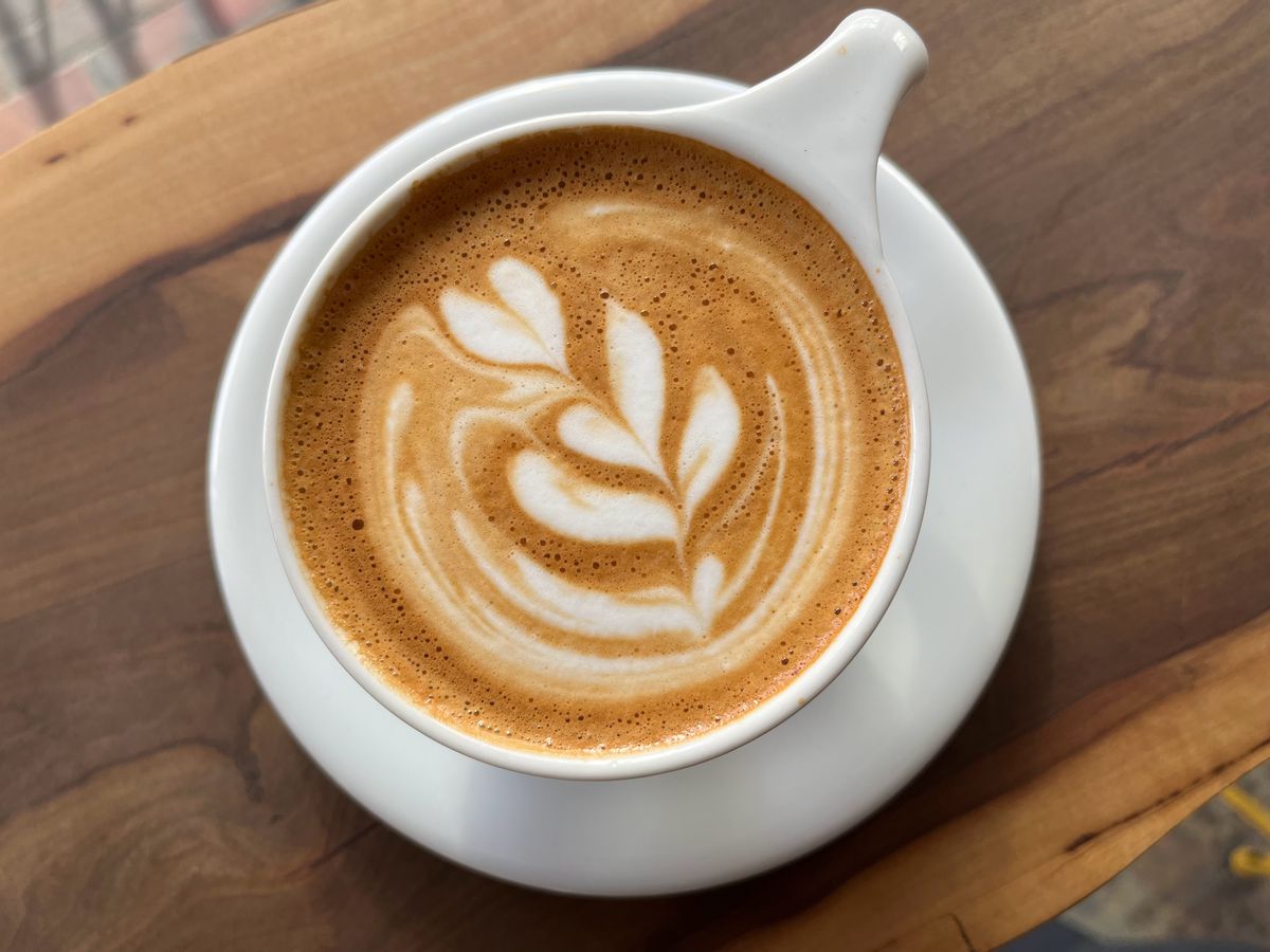 A cup of mouth-watering coffee with a flower drawn on it using fresh milk