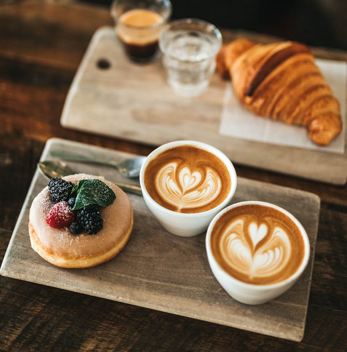 A donut, a croissant and two cups of coffee